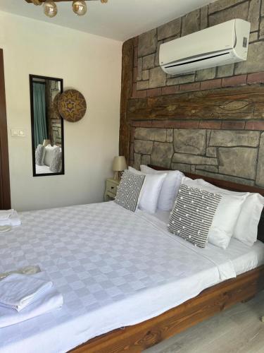 a bedroom with a bed with a stone wall at Pupa Alaçatı Butik Otel in Cesme
