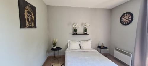 a white bedroom with a bed and two side tables at Appartement Proche DisneyLand Paris in Montévrain