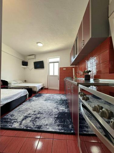 a room with two beds and a kitchen with a rug at Apartmani Andric in Trebinje