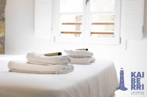 una pila de toallas sentadas encima de una cama en Ubilla by Kaiberri Inmo, en Hondarribia