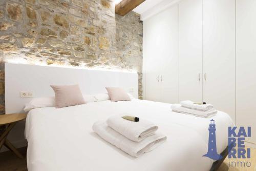 Un dormitorio con una cama blanca con toallas. en Ubilla by Kaiberri Inmo en Hondarribia