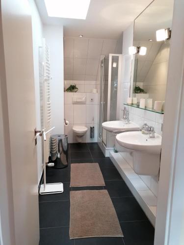 a bathroom with two sinks and a toilet and a mirror at Appartment Obergeschoß in Bad Zwischenahn