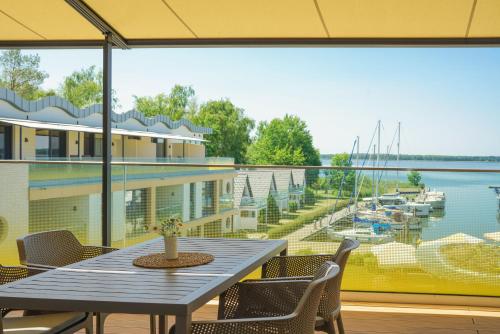 a table and chairs on a balcony with a view of a marina at Appartements "Zum Leuchtturm" Hafen Rankwitz Insel Usedom in Rankwitz