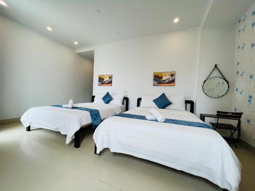 two beds in a white room with a clock on the wall at candyinn in Hue