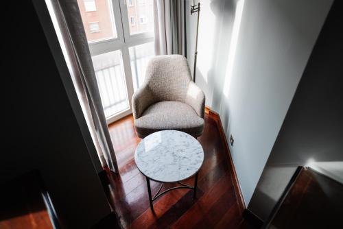 a room with a chair and a table and a window at RICE Reyes Católicos in Burgos