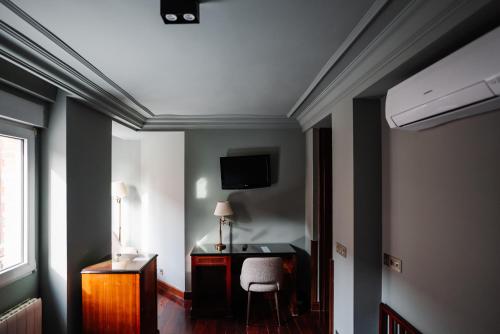 a room with a desk and a tv on the ceiling at RICE Reyes Católicos in Burgos