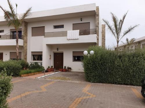 un bâtiment blanc avec des palmiers devant lui dans l'établissement Villa Sidi Rahal Casablanca, à Sidi Rahal