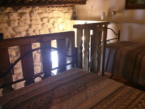 a bedroom with two beds and a stone wall at Anticu Dammusu in Scicli