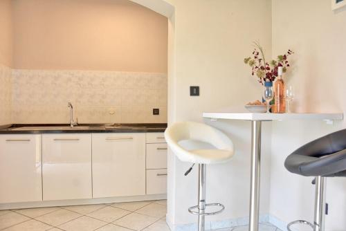 una cucina con armadi bianchi, lavandino e tavolo di Studio Apartment Petra 3 a Kirmenjak
