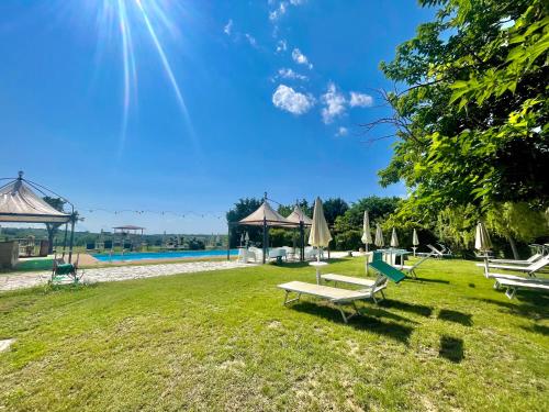 un parque con bancos y sombrillas en el césped en Casale Baldelli Apartments, en Castiglione del Lago