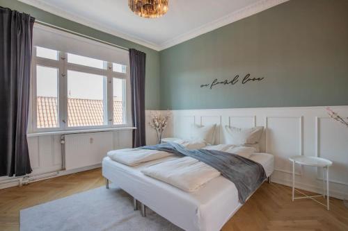 a bedroom with a white bed with a sign on the wall at Amazing Royal Suite in Helsingør
