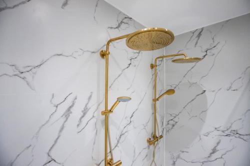 a shower with gold fixtures and a marble wall at Amazing Royal Suite in Helsingør