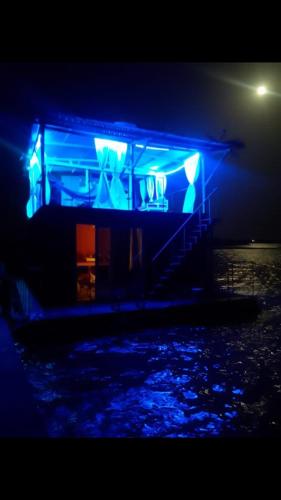 a blue building with lights on the water at night at Maison flottante in Ndangane
