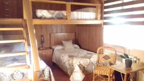 a bedroom with bunk beds with a bed and a chair at LOS ARCOS in Las Labores