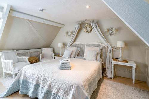 a bedroom with a white bed and a chair at Guesthouse B&B De Loverlij in Jabbeke