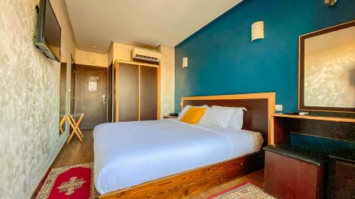 a bedroom with a white bed and a blue wall at Hôtel Belle Vue et Spa in Meknès