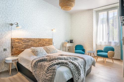 a bedroom with a bed and two blue chairs at le clos grillet in La Chambre