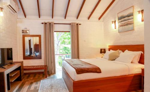 a bedroom with a bed and a television and a window at Tepraas Sigiriya in Sigiriya