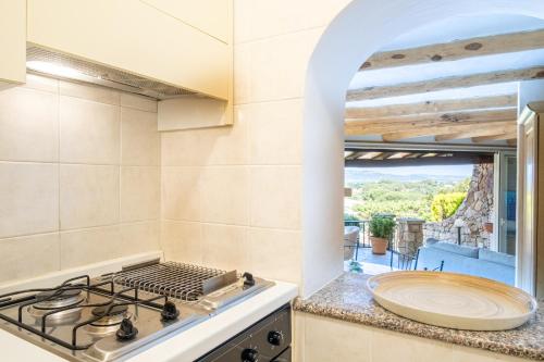 uma cozinha com um fogão, um lavatório e uma janela em Villa Baja Sardinia con piscina e vista em Baja Sardinia