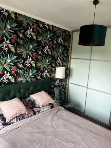 a bedroom with a bed with a floral wall at Apartament Bieszczadzka in Szczecin