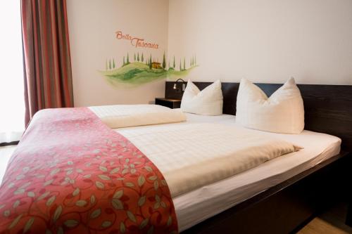 a bedroom with a large bed with white pillows at Hotel La Toscana Nähe Europapark in Ringsheim