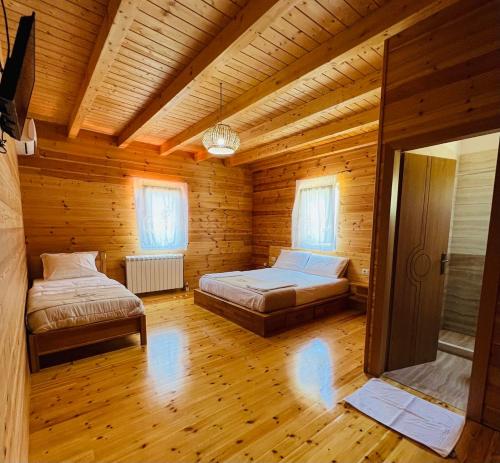 a bedroom with two beds in a wooden cabin at Bujtina Dini in Rubik
