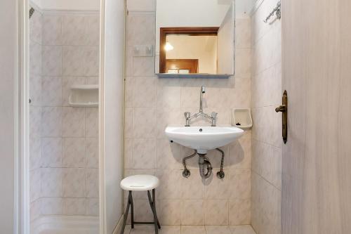 a bathroom with a sink and a mirror and a stool at Areti Orfeas Apartment 6 in Vasilikos