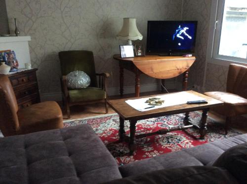 uma sala de estar com um sofá, uma mesa e uma televisão em Le Mas Maison de village em Vabre
