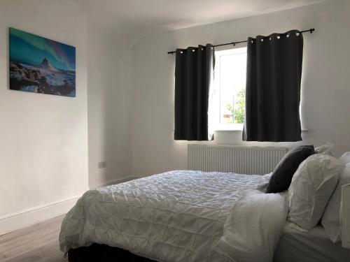 a bedroom with a bed and a window with black curtains at Immaculate 3-Bed House in Nottingham in Nottingham