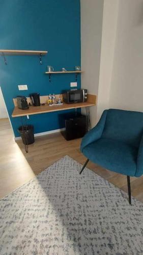 a room with a blue chair and a table with a microwave at Mister Hinster - studio tout confort centre ville Nogent-le-Rotrou - 1e étage in Nogent-le-Rotrou