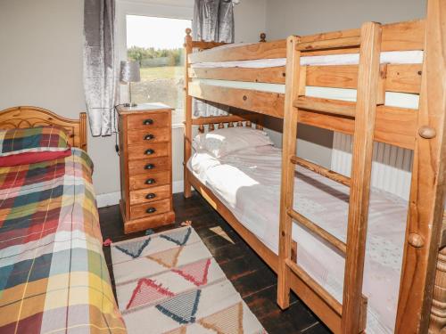 a bedroom with two bunk beds and a dresser at St Justinians in St. Davids