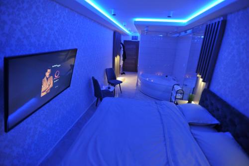 Cette chambre bleue comprend un lit et une télévision. dans l'établissement Apartman De Lux - Cacak, à Čačak