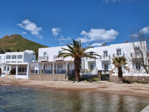 Grikos的住宿－銀灘酒店，一座棕榈树成荫的白色建筑,毗邻一片水体