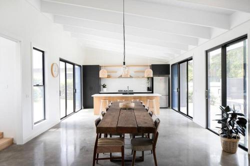 a dining room with a table and some windows at Bawley Beach House, Short Walk to Bawley Beach in Bawley Point