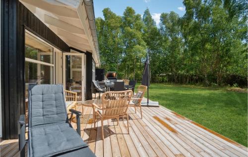 a wooden deck with chairs and a table and an umbrella at 3 Bedroom Awesome Home In Gørlev in Gørlev