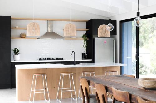 a kitchen with a wooden table and a kitchen with a refrigerator at Bawley Beach House, Short Walk to Bawley Beach in Bawley Point