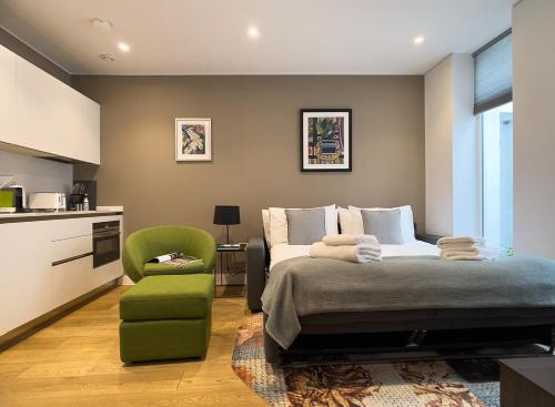 a bedroom with a bed and a green chair at Mirabilis Apartments - Bayham Street in London