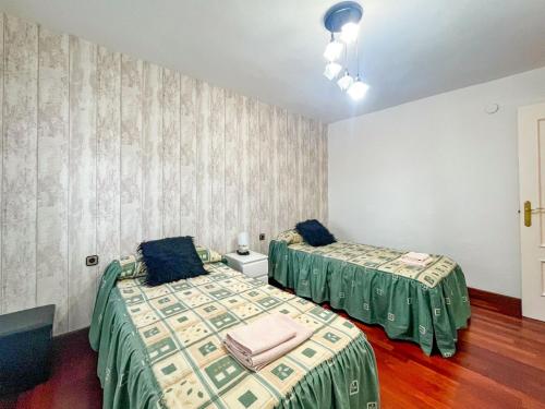 two beds in a room with green sheets at APARTAMENTO BERMEOKOSUSTRAIAK-60 m2 wifi gratis in Bermeo