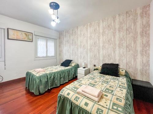 a bedroom with two beds and a window at APARTAMENTO BERMEOKOSUSTRAIAK-60 m2 wifi bicicletas gratis in Bermeo