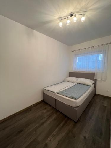 a white bedroom with a bed and a window at Modern Apartman in Szeged