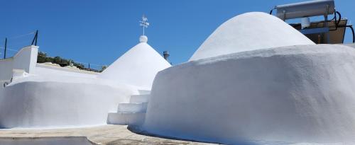 un groupe de bâtiments blancs avec un ciel bleu en arrière-plan dans l'établissement TRULLO CARMEN, à San Michele Salentino