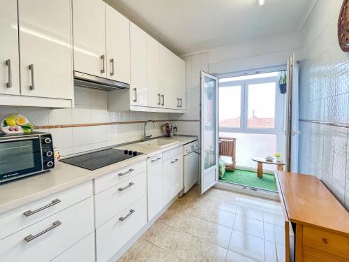a kitchen with white cabinets and a large window at APARTAMENTO BERMEOKOSUSTRAIAK-60 m2 wifi bicicletas gratis in Bermeo