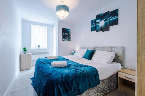 a bedroom with a large bed with a blue blanket at 1BR & 2BR Apt -for CONTRACTORS- free PARKING close to EVERTON & ANFIELD stadium, Liverpool City Centre managed by Chique Properties Ltd in Liverpool
