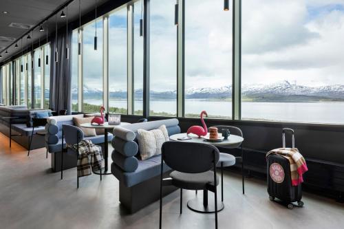 a restaurant with a view of the water and mountains at Moxy Tromso in Tromsø