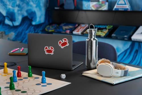 a table topped with a laptop computer and a bottle at Moxy Tromso in Tromsø