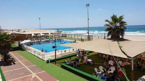 a large swimming pool next to the beach with people sitting at דירת 2 חדרים בטיילת בת ים in Bat Yam
