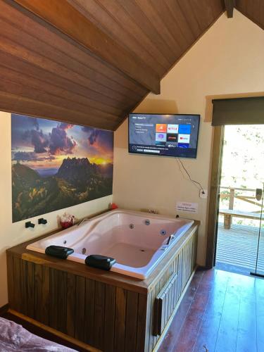a large bath tub in a room with a tv at Recanto Lira I in Monte Verde