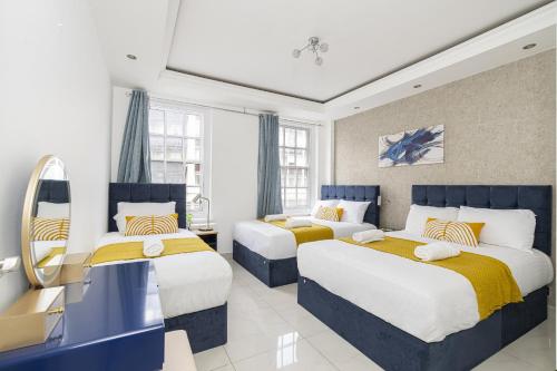 ロンドンにあるMarble Arch Apartmentsのベッドルーム1室(黄色と青色のベッド2台付)