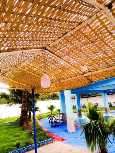 a wooden pergola with tables and chairs under it at Hotel Complex Europe in Guercif