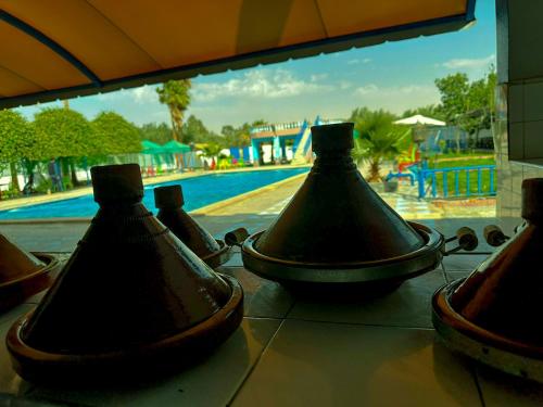 un grupo de jarrones sentados en una mesa cerca de una piscina en Hotel Complex Europe, en Guercif